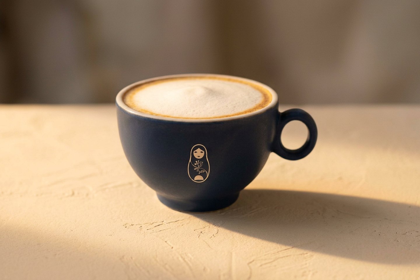 Six ounce cappuccino with a thick even foam layer in a matte navy cup and saucer on a marble table at Krasivo Beauty Cafe, Upper East Side