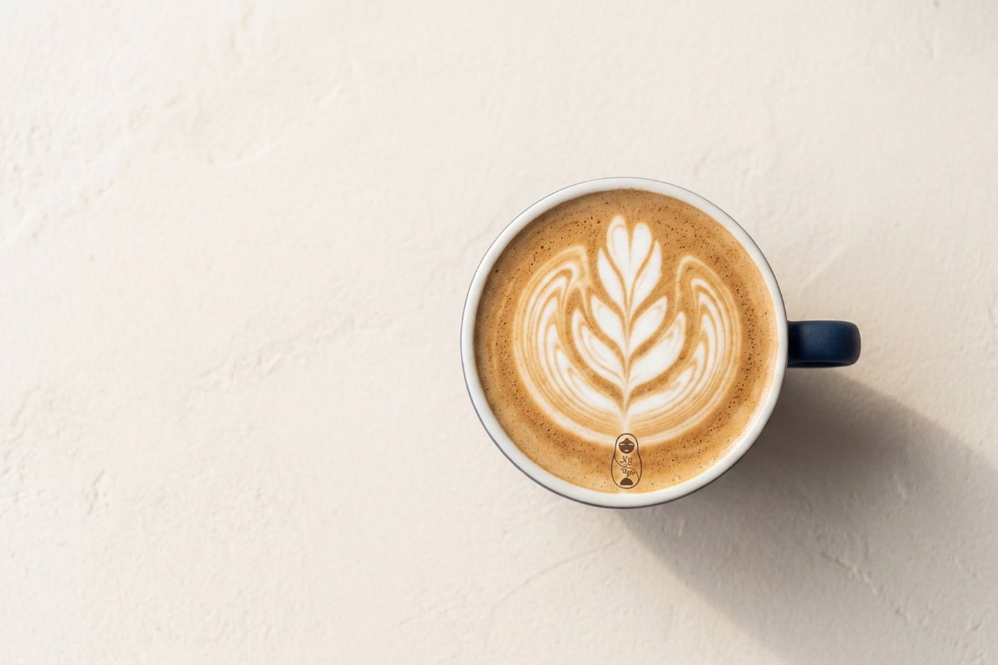 Twelve ounce latte with a thin layer of microfoam in a matte navy cup on a marble counter under brass lamp light at Krasivo Beauty Cafe, Upper East Side